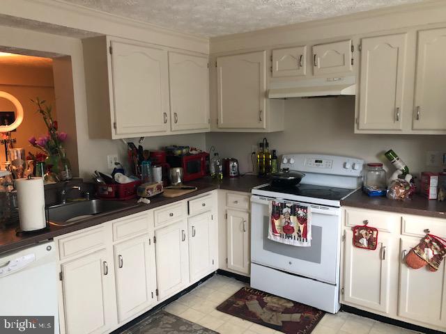 7516 Mandan Road Greenbelt, MD 20770 - Photo 11 of 15 a kitchen with white cabinets and white appliances