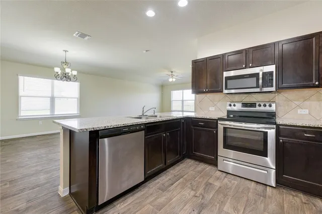a kitchen with stainless steel appliances granite countertop a stove a sink and a microwave