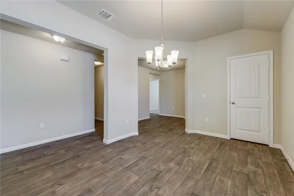 a view of empty room with wooden floor and chandelier