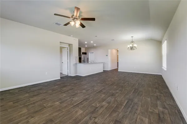 a view of empty room with wooden floor and ceiling fan