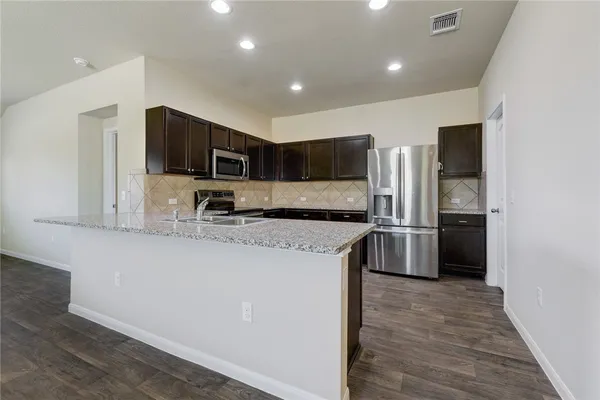 a kitchen with stainless steel appliances granite countertop a refrigerator a stove a sink and a microwave