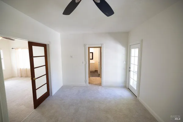 an empty room with windows fireplace and fan