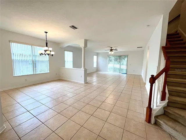 an empty room with windows and ceiling fan