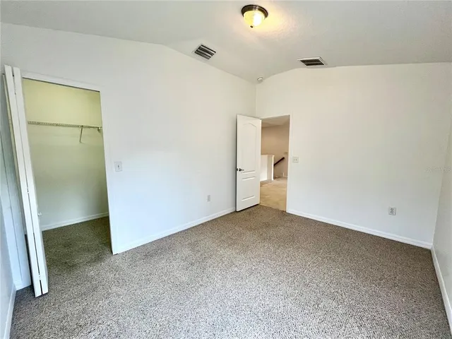 a white house with a big yard plants and large trees