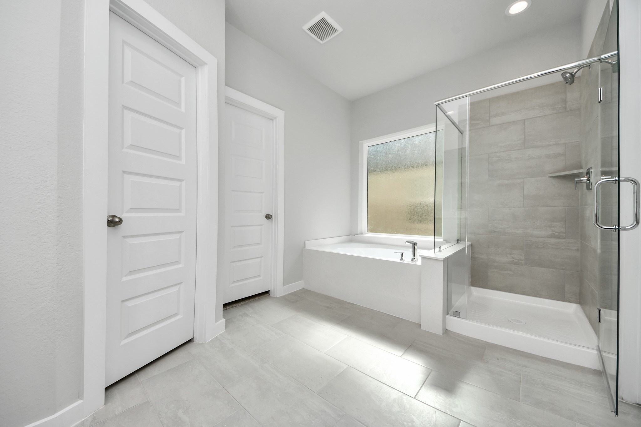 2922 Burris Park Drive Spring, TX 77373 - Photo 23 of 37 Escape to a spa-like oasis in this primary bathroom. Enjoy a walk-in shower with tile surround, a separate garden tub with custom detailing, and an elegant vanity featuring light countertops, modern hardware, and beautiful vanity lights. Experience luxury and relaxation in every detail. Sample photo of completed home with similar floor plan. Actual colors and selections may vary.
