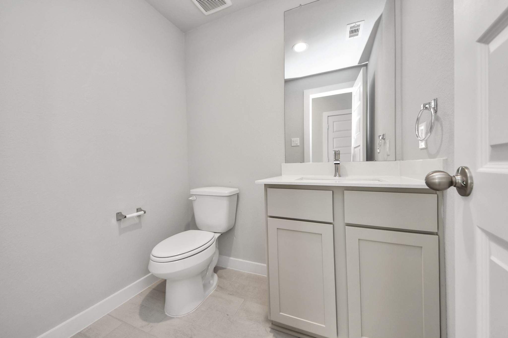 2922 Burris Park Drive Spring, TX 77373 - Photo 5 of 37 Sophisticated half bathroom adorned with contemporary finishes. The elegant 5-panel door welcomes you to a space where style meets functionality. Notice the sleek hardware accents that add a touch of modern charm. The vanity boasts light-colored countertops, beautifully complemented by a tasteful recessed light, creating a well-lit and inviting atmosphere. Sample photo of completed home with similar floor plan. Actual colors and selections may vary.