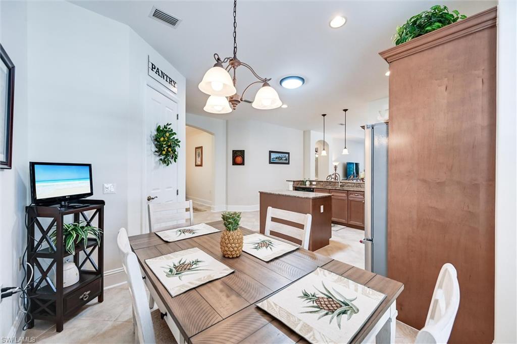 7587 Moorgate Point Way Naples, FL 34113 - Photo 28 of 50 Dining area featuring a wood-finish dining table and a decorative chandelier