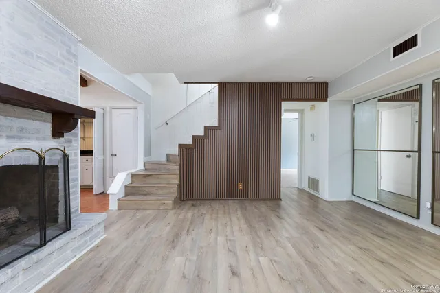 a view of a livingroom with wooden floor and a kitchen
