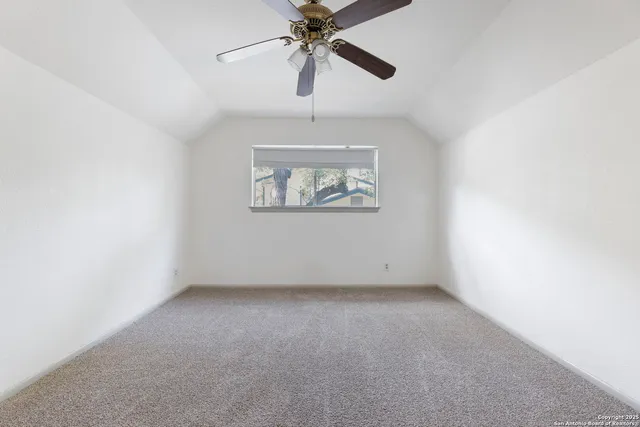 an empty room with a window and a ceiling fan