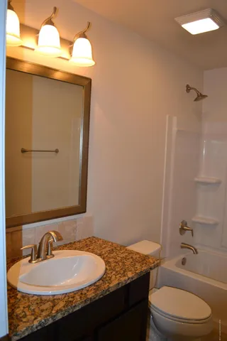 a bathroom with a granite countertop sink toilet and shower