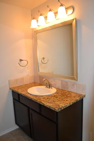 a bathroom with a granite countertop sink and a mirror