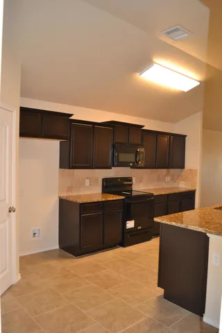 a kitchen with stainless steel appliances kitchen island granite countertop a refrigerator and a sink
