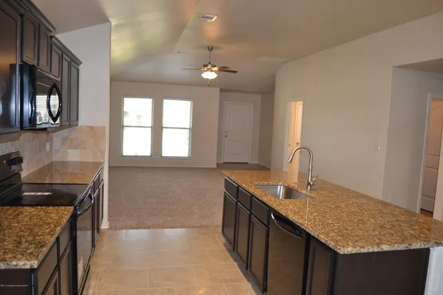 a kitchen with granite countertop a sink stainless steel appliances cabinets and a counter top space