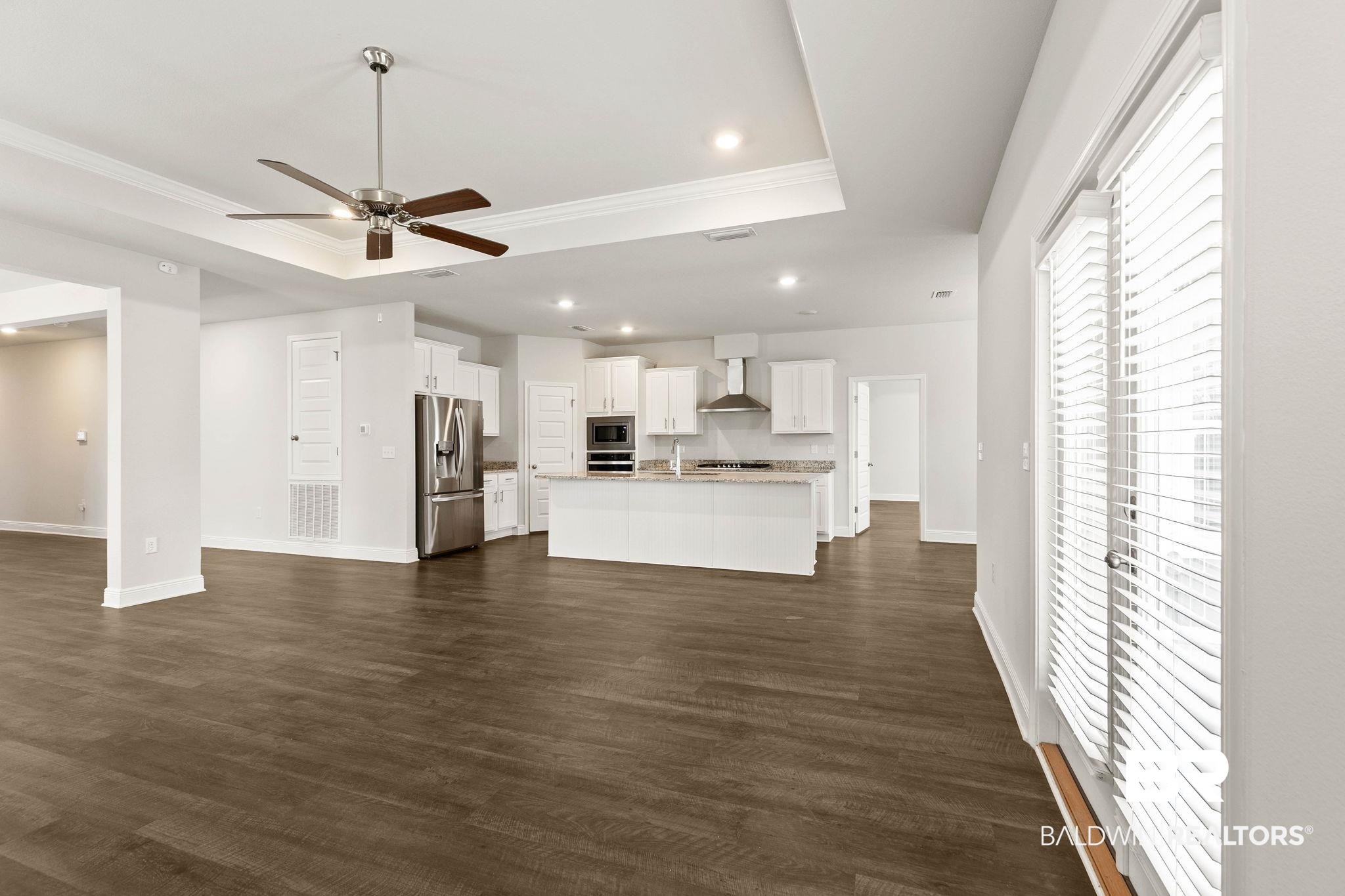 9448 Amethyst Drive Daphne, AL 36526 - Photo 11 of 61 Unfurnished living room with ceiling fan, a raised ceiling, ornamental molding, recessed lighting, and dark wood-type flooring