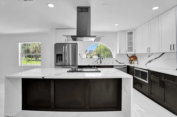 a kitchen with kitchen island granite countertop a sink cabinets and wooden floor