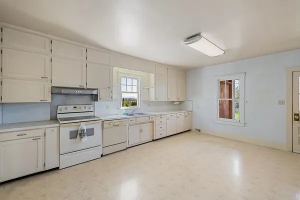 a large white kitchen with cabinets
