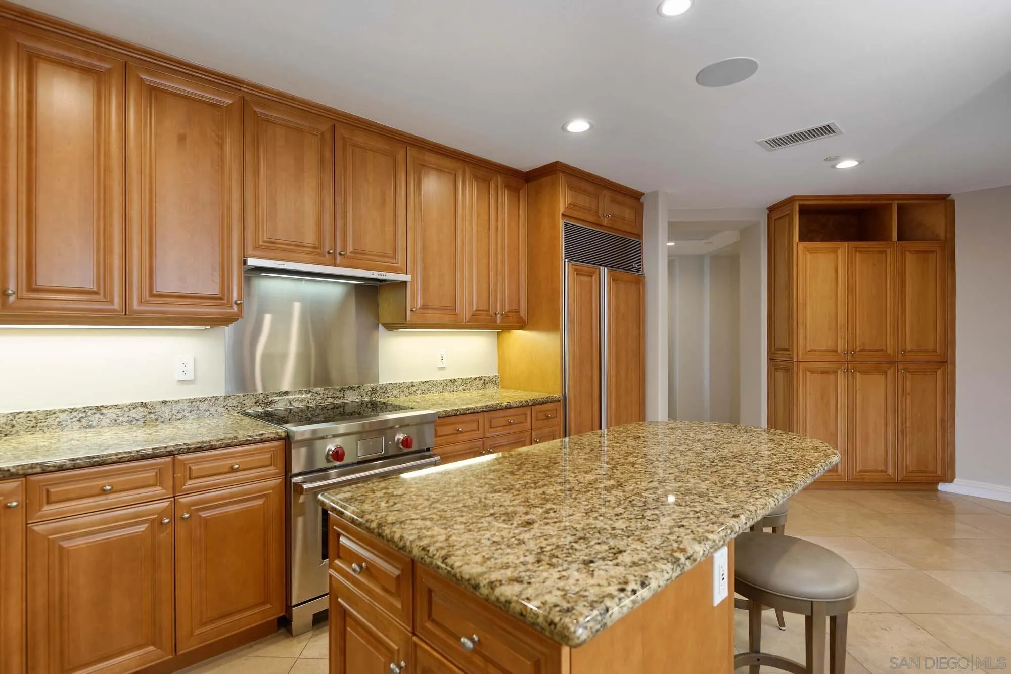 464 Prospect Street, Unit 101 La Jolla, CA 92037 - Photo 12 of 43 a kitchen with kitchen island granite countertop wooden cabinets and a granite counter tops