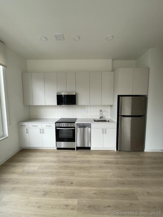 42 John Street, Unit 506 Stamford, CT 06902 - Photo 22 of 23 a kitchen with stainless steel appliances granite countertop a refrigerator sink and stove