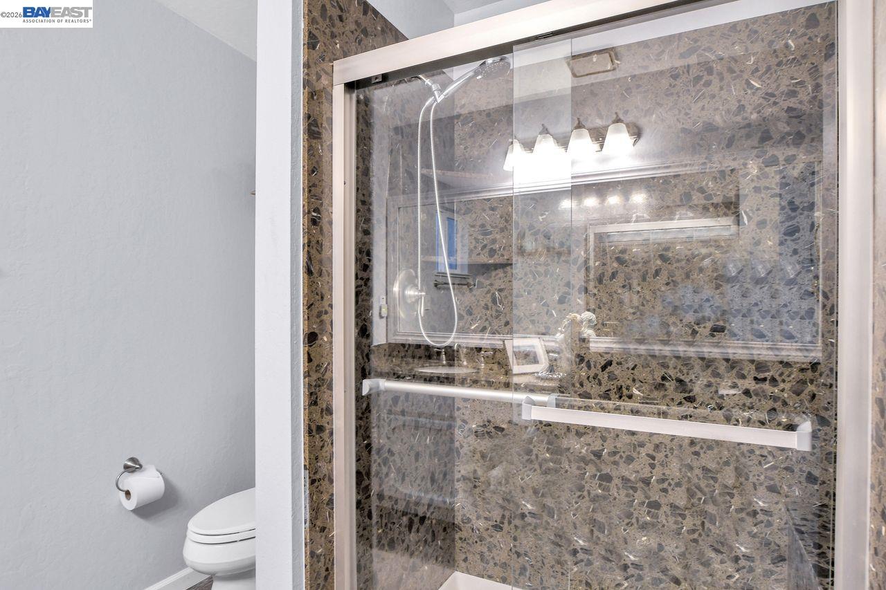 2033 Sand Point Road Discovery Bay, CA 94505 - Photo 22 of 27 a bathroom with a granite countertop mirror a toilet and a shower