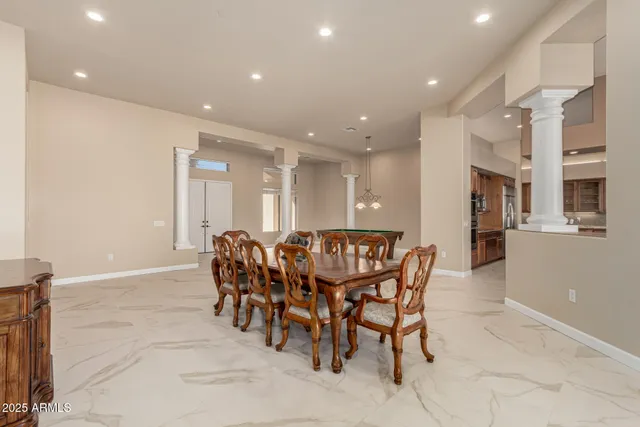 a kitchen with stainless steel appliances granite countertop a stove top oven a sink a dining table and chairs with wooden floor