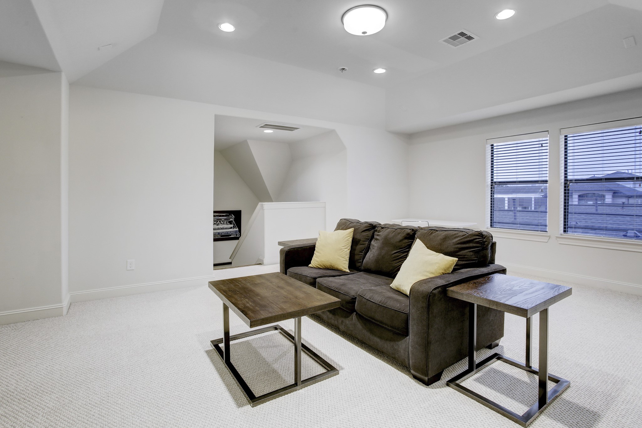 5506 Darling Street Houston, TX 77007 - Photo 19 of 23 The large 3rd Floor Game Room (or 4th Bedroom) has a sleeper sofa with side tables, a coffee table, a wall-mounted TV, large windows, a raised ceiling with recessed and overhead lighting, and an ensuite full bath and walk-in closet.