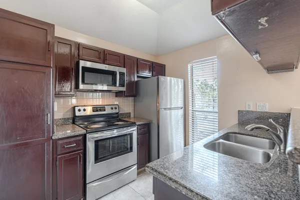 a kitchen with stainless steel appliances granite countertop a refrigerator stove and sink