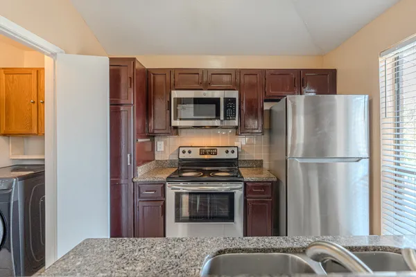 a kitchen with granite countertop a stove and a refrigerator