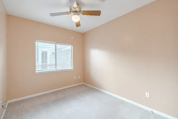 an empty room with a window and a fan