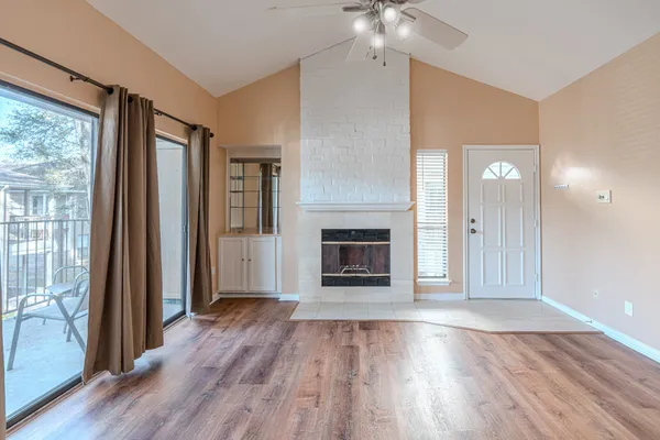 an empty room with wooden floor fireplace and windows
