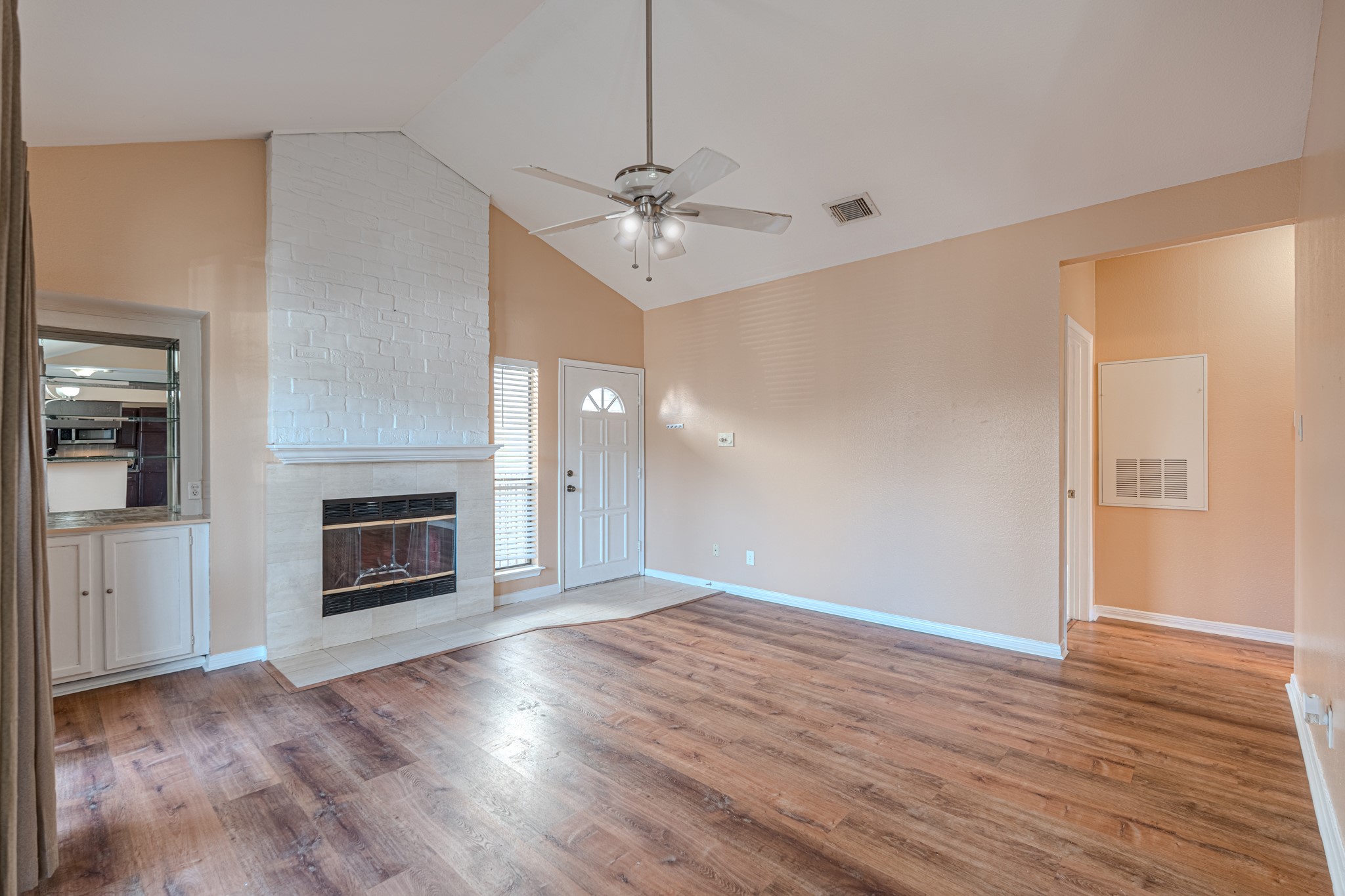 3500 Tangle Brush Drive, Unit 182 Spring, TX 77381 - Photo 8 of 24 an empty room with wooden floor a fireplace a ceiling fan and a kitchen view