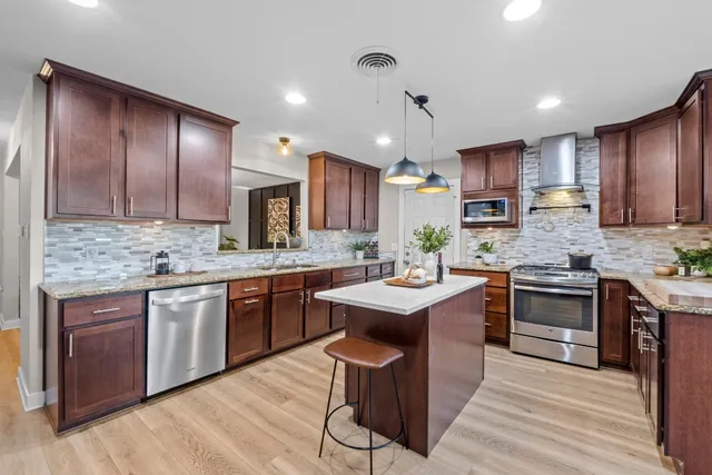 a kitchen with kitchen island granite countertop wooden cabinets and white appliances