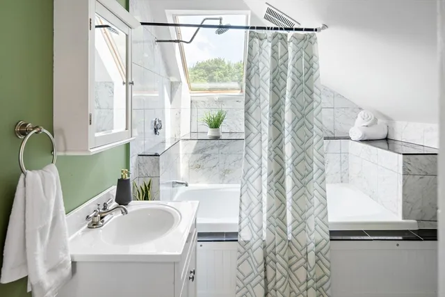 a bathroom with a sink and mirror with bathtub