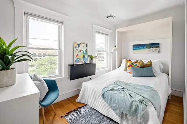 a bed sitting in a bedroom next to a window with potted plant