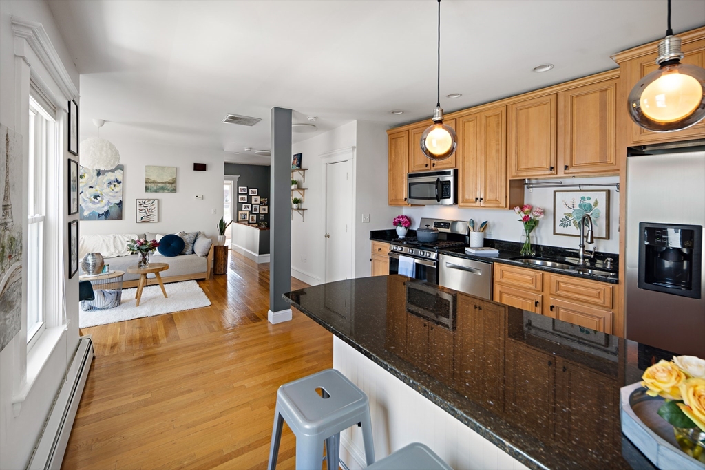 32 Harvard Street, Unit 2 Waltham, MA 02453 - Photo 6 of 32 a kitchen with stainless steel appliances granite countertop a stove top oven a dining table and chairs with the living room