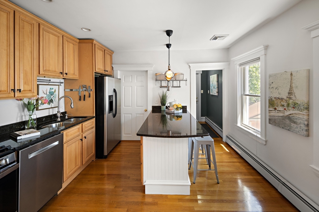32 Harvard Street, Unit 2 Waltham, MA 02453 - Photo 8 of 32 a kitchen with stainless steel appliances granite countertop a stove top oven a refrigerator a sink and dishwasher with wooden floor