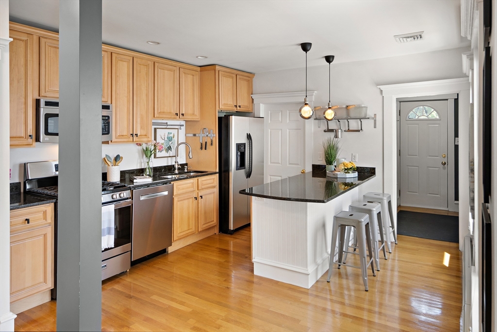 32 Harvard Street, Unit 2 Waltham, MA 02453 - Photo 9 of 32 a kitchen with stainless steel appliances a refrigerator a stove a sink dishwasher and white cabinets with wooden floor
