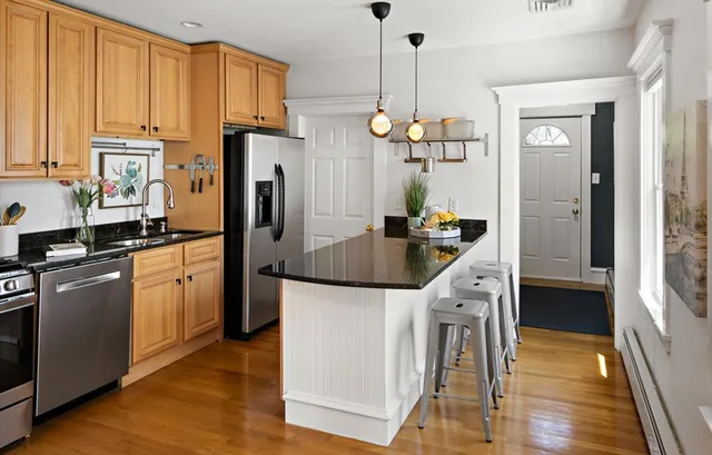 a kitchen with a refrigerator a stove a sink and dishwasher with wooden floor