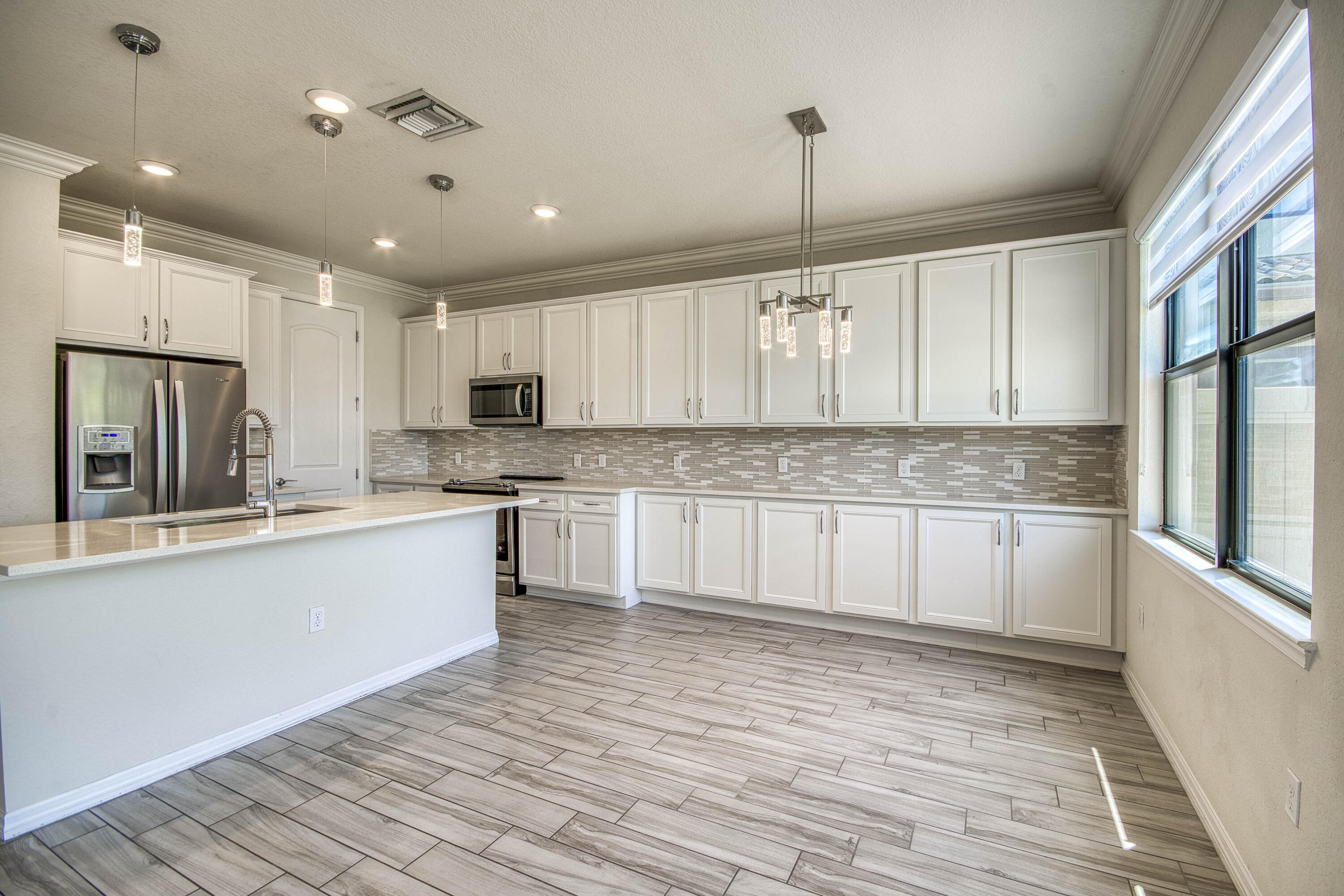8301 Rearing Lane Lake Worth, FL 33467 - Photo 16 of 33 a large kitchen with stainless steel appliances granite countertop a stove a sink dishwasher and a refrigerator with wooden floor