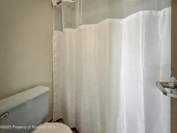 a white toilet sitting next to a white curtain