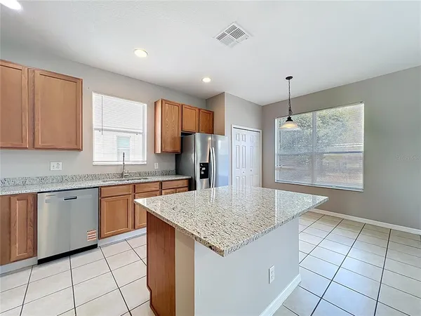 a large kitchen with stainless steel appliances kitchen island granite countertop a stove a sink and a refrigerator