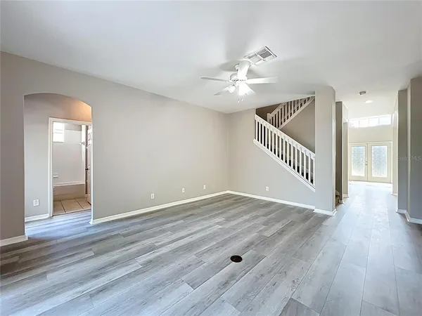 a view of a room with wooden floor and a chandelier fan