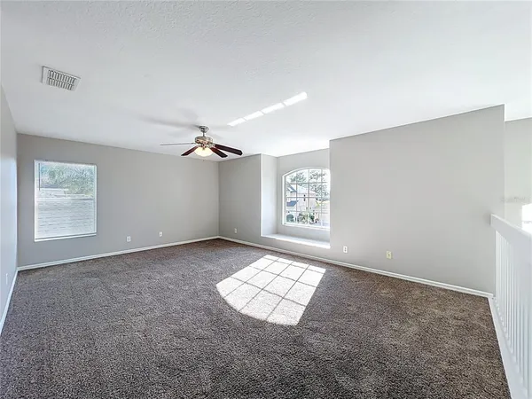 an empty room with windows and chandelier fan