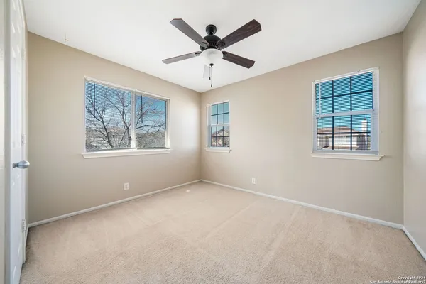 an empty room with windows and ceiling fan