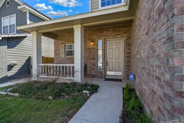 a view of a house with brick walls and a yard with plants