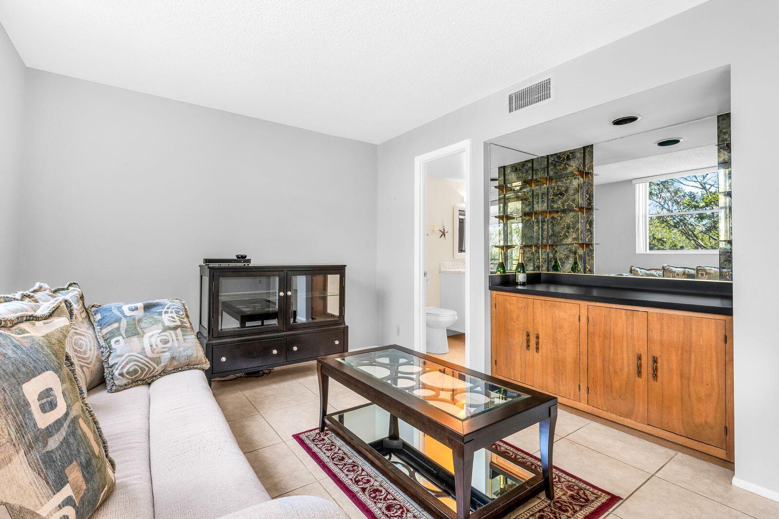 6461 Northwest 2nd Avenue, Unit 403 Boca Raton, FL 33487 - Photo 12 of 22 a living room with furniture a flat screen tv and a window
