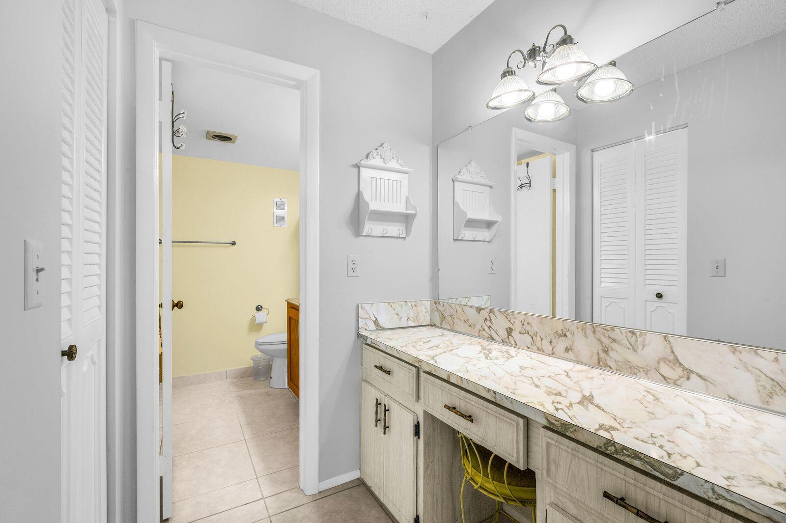 6461 Northwest 2nd Avenue, Unit 403 Boca Raton, FL 33487 - Photo 17 of 22 a spacious bathroom with a granite countertop sink a toilet and a mirror