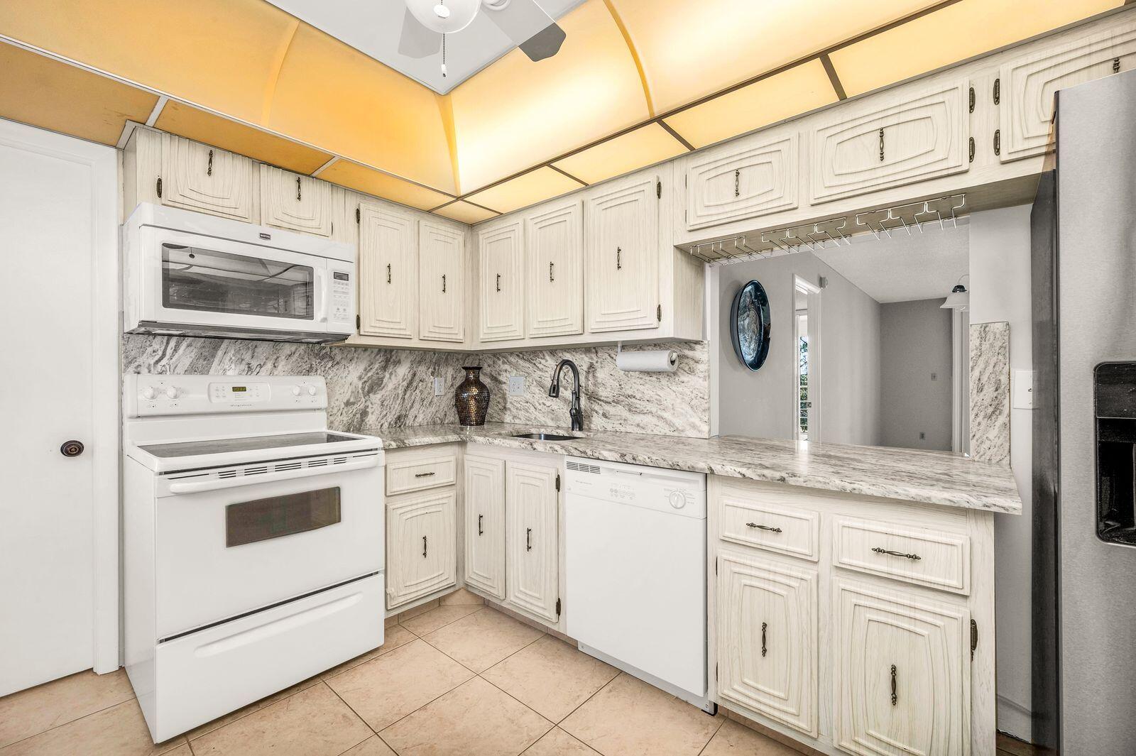 6461 Northwest 2nd Avenue, Unit 403 Boca Raton, FL 33487 - Photo 3 of 22 a kitchen with granite countertop white cabinets and white stainless steel appliances