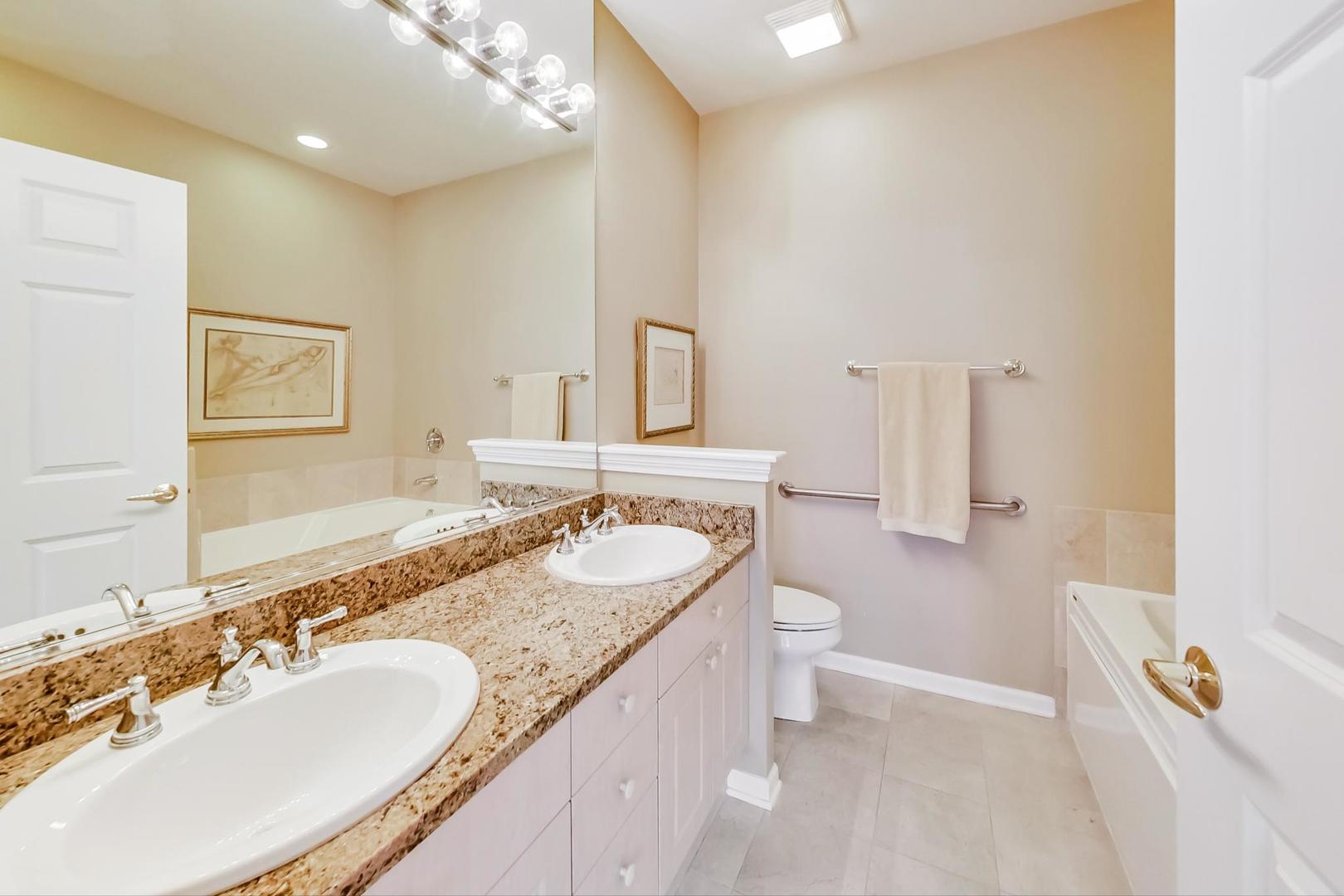 7742 North Sheridan Road, Unit 1L Chicago, IL 60626 - Photo 21 of 40 a bathroom with a granite countertop double vanity sink a mirror and a