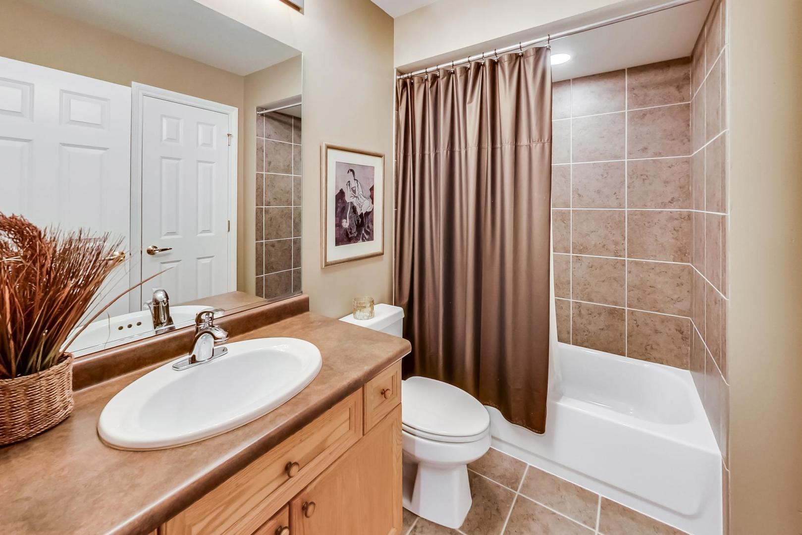 7742 North Sheridan Road, Unit 1L Chicago, IL 60626 - Photo 31 of 40 a bathroom with a sink a toilet a mirror and shower