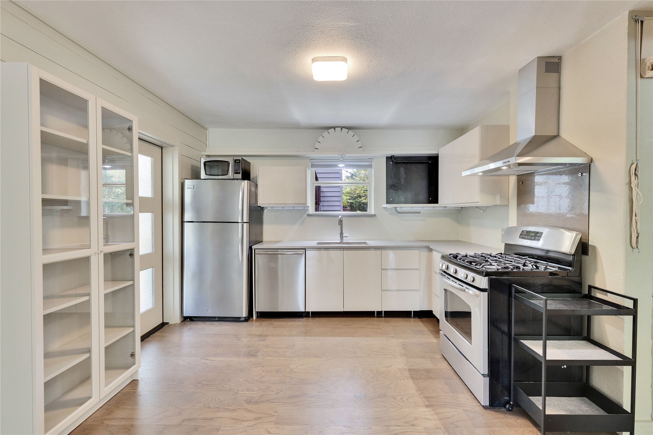 1306 Norwood Road, Unit A Austin, TX 78722 - Photo 8 of 21 Modern kitchen with stainless steel appliances and smooth wood flooring for easy meal prep.